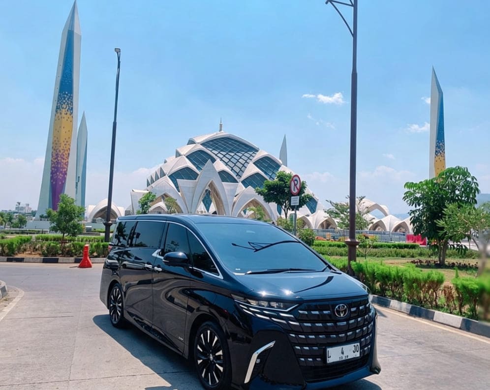 Toyota Alphard white luxury MPV on highway at night with city lights
